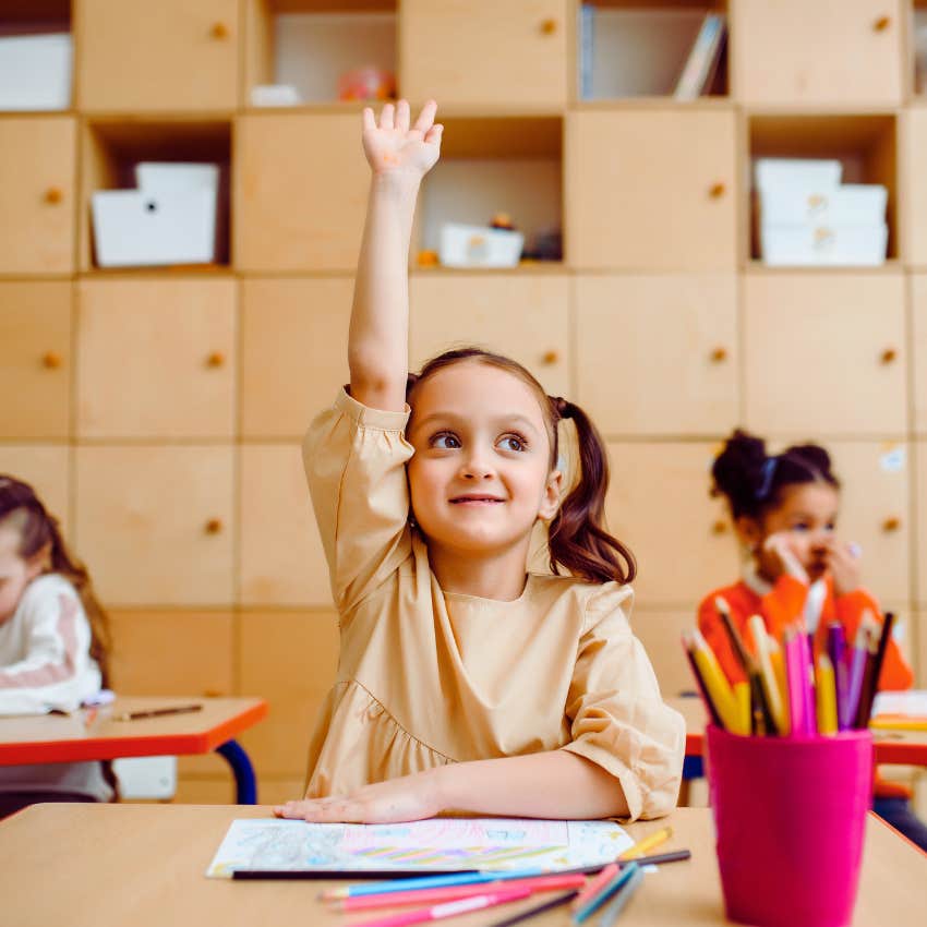 student raising her hand in classroom