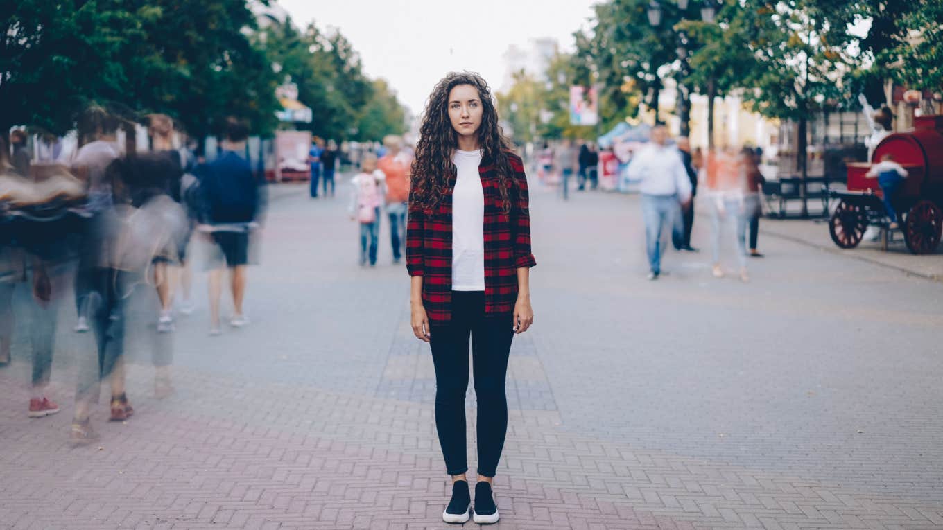 woman stands isolated in bustling crowd of people