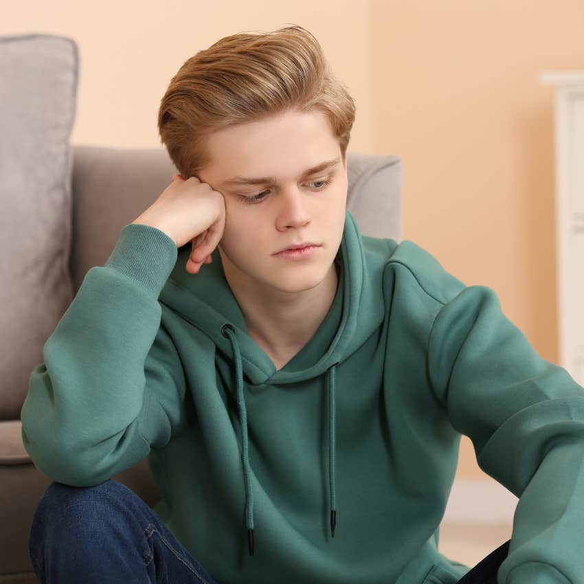 upset teenage boy sitting alone in room