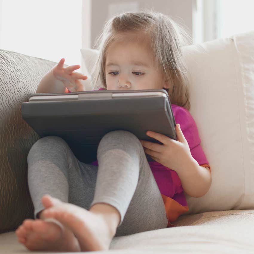 toddler using a tablet while sitting on the couch