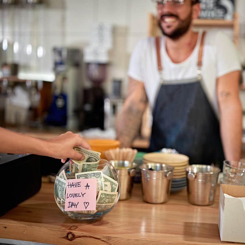 satisfied customer in coffee shop leaving tip in a bowl with a positive message on a sticker.