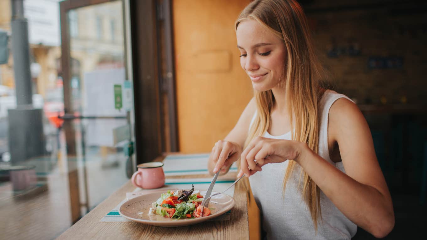  smiling woman eating salad at restaurant