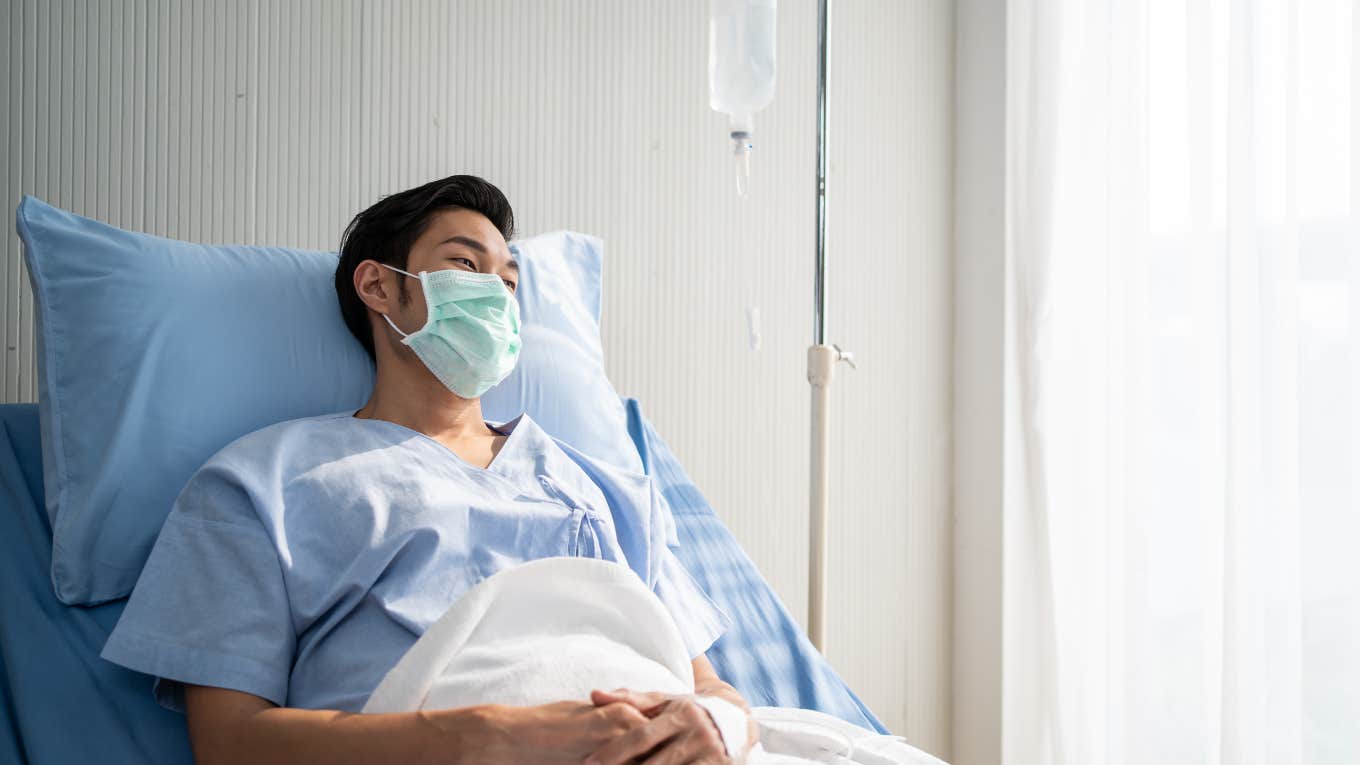 masked man laying in hospital bed