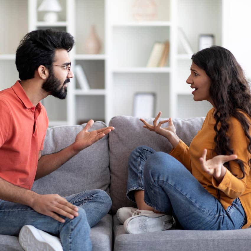young couple arguing while sitting on couch in living room