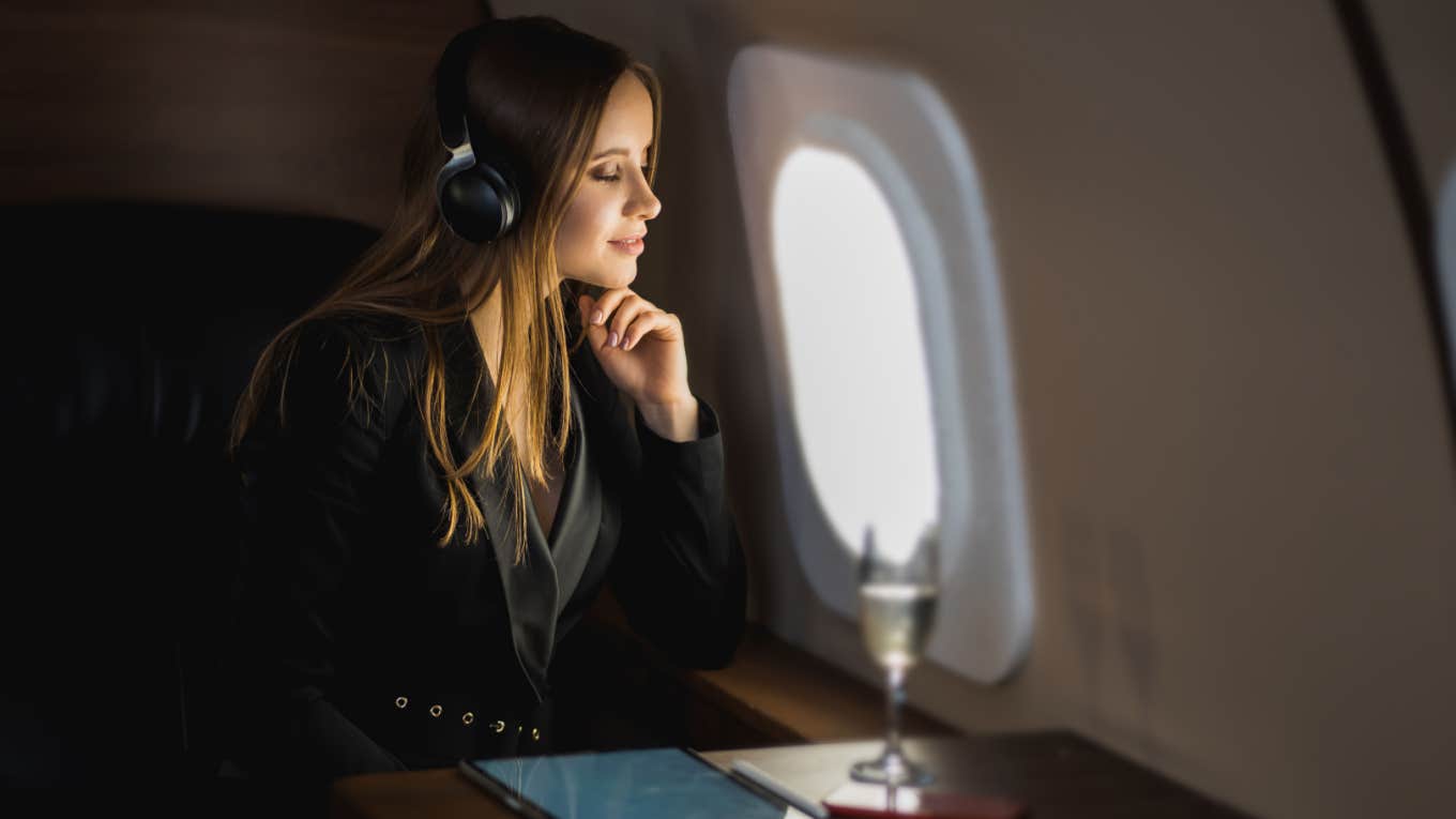 woman relaxes in business class flight with glass of champagne