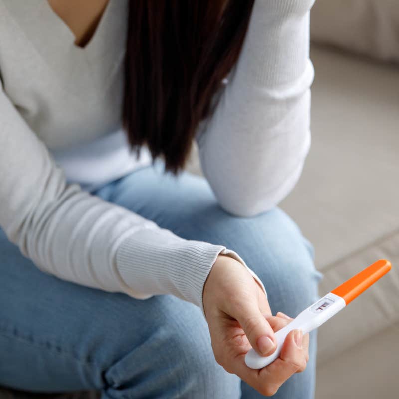 woman holds a pregnancy test in her hand.