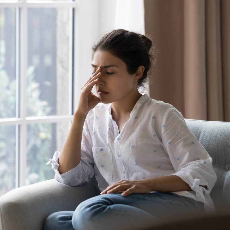 frustrated young woman suffering from headache, touching face with closed eyes