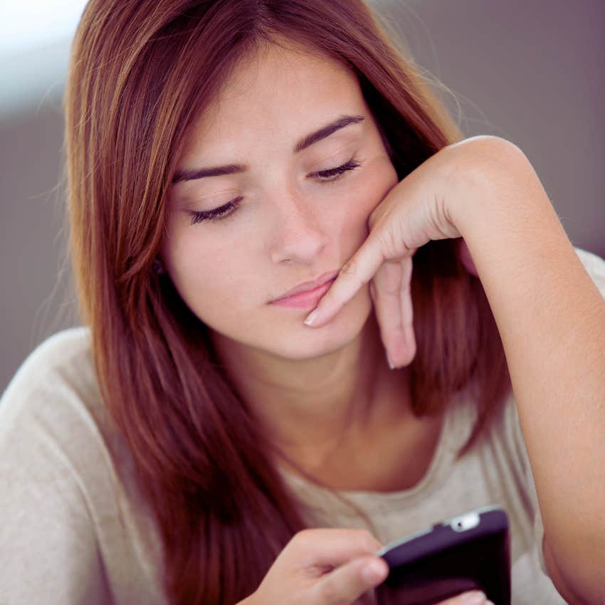 woman looking seriously at her phone while texting