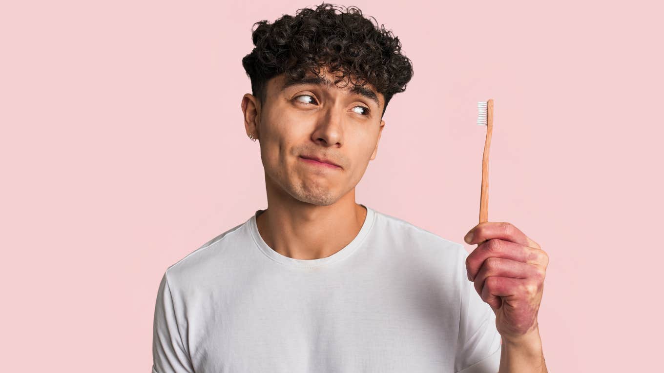 Man refusing to brush his teeth while looking at toothbrush. 