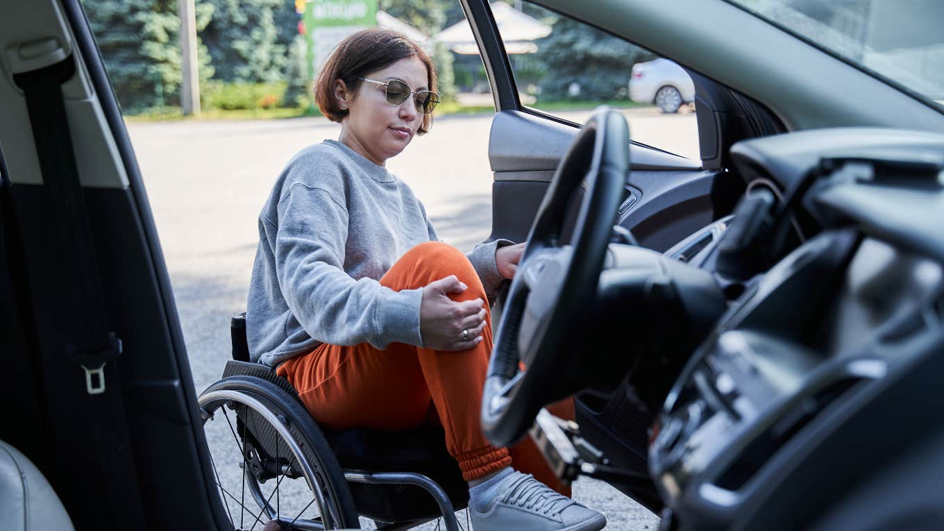 Woman opening door of her car and getting inside from sitting on wheelchair