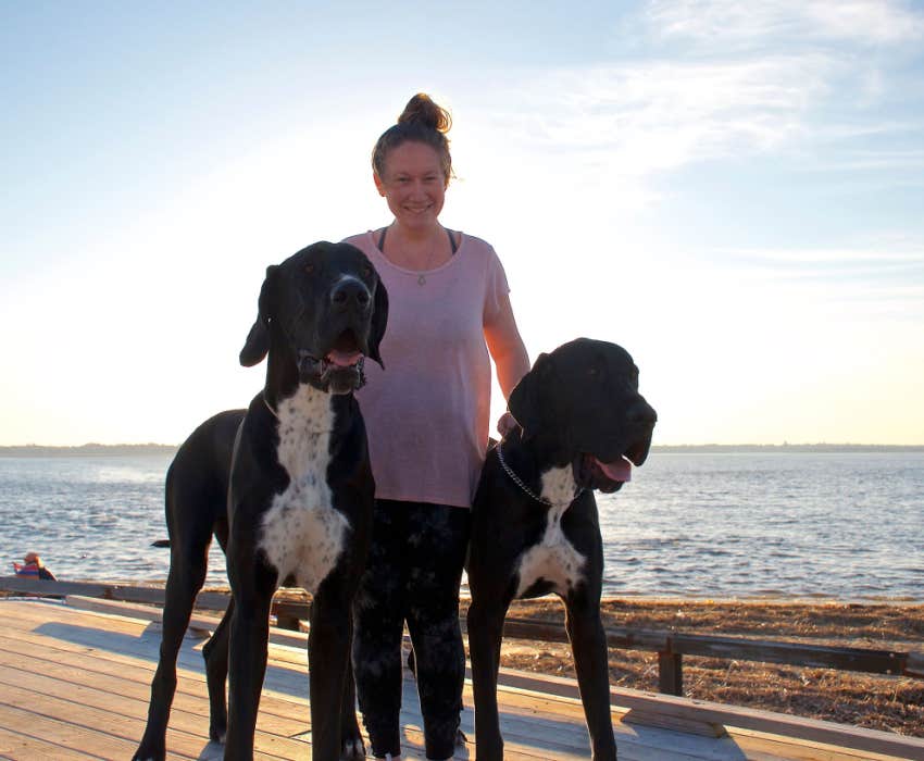 dog owner walks her two great danes outside by the beach