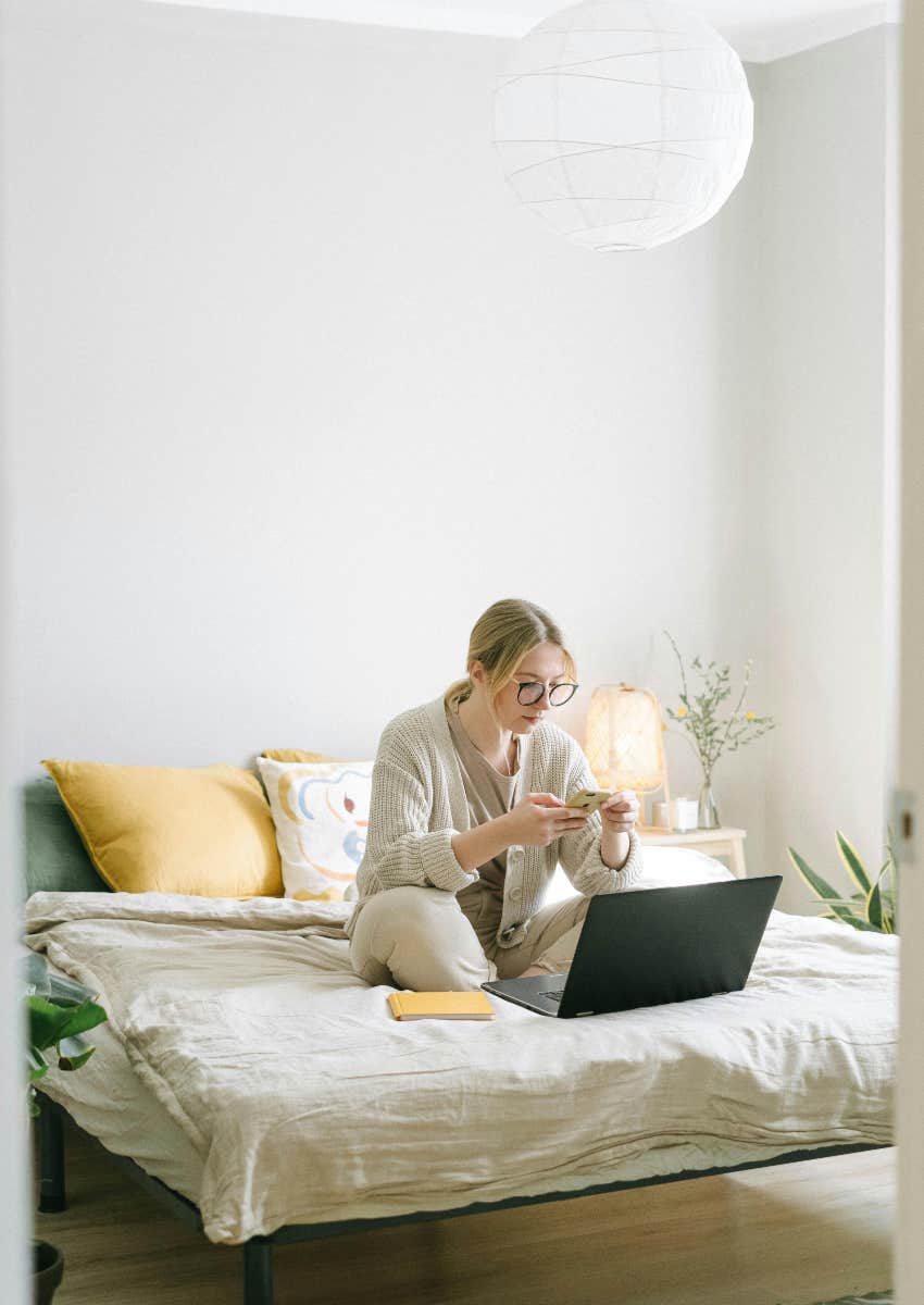 woman sitting on bed using laptop