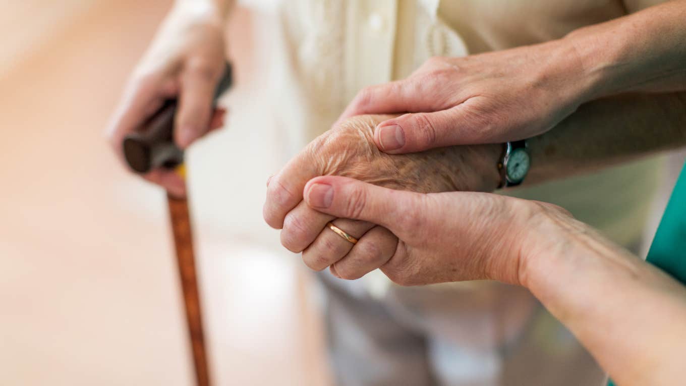 person holding elderly woman's hand
