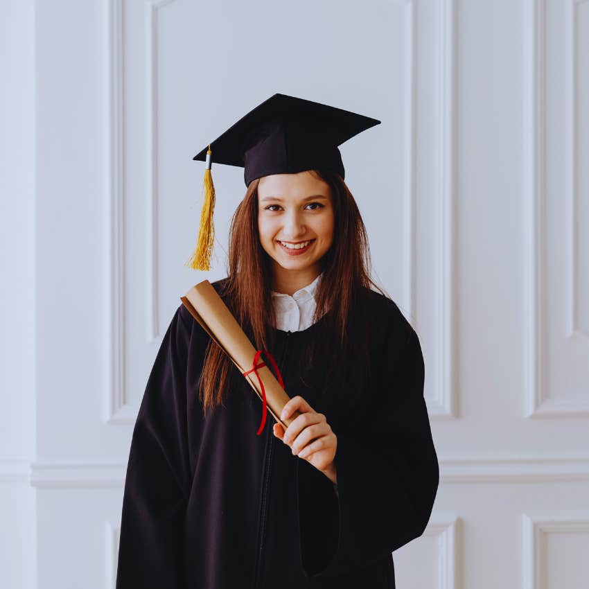young woman in cap and gown holding college diploma