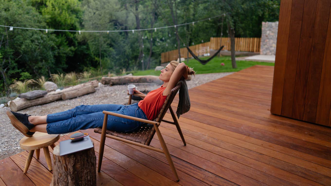 woman relaxes in lawn chair on back porch