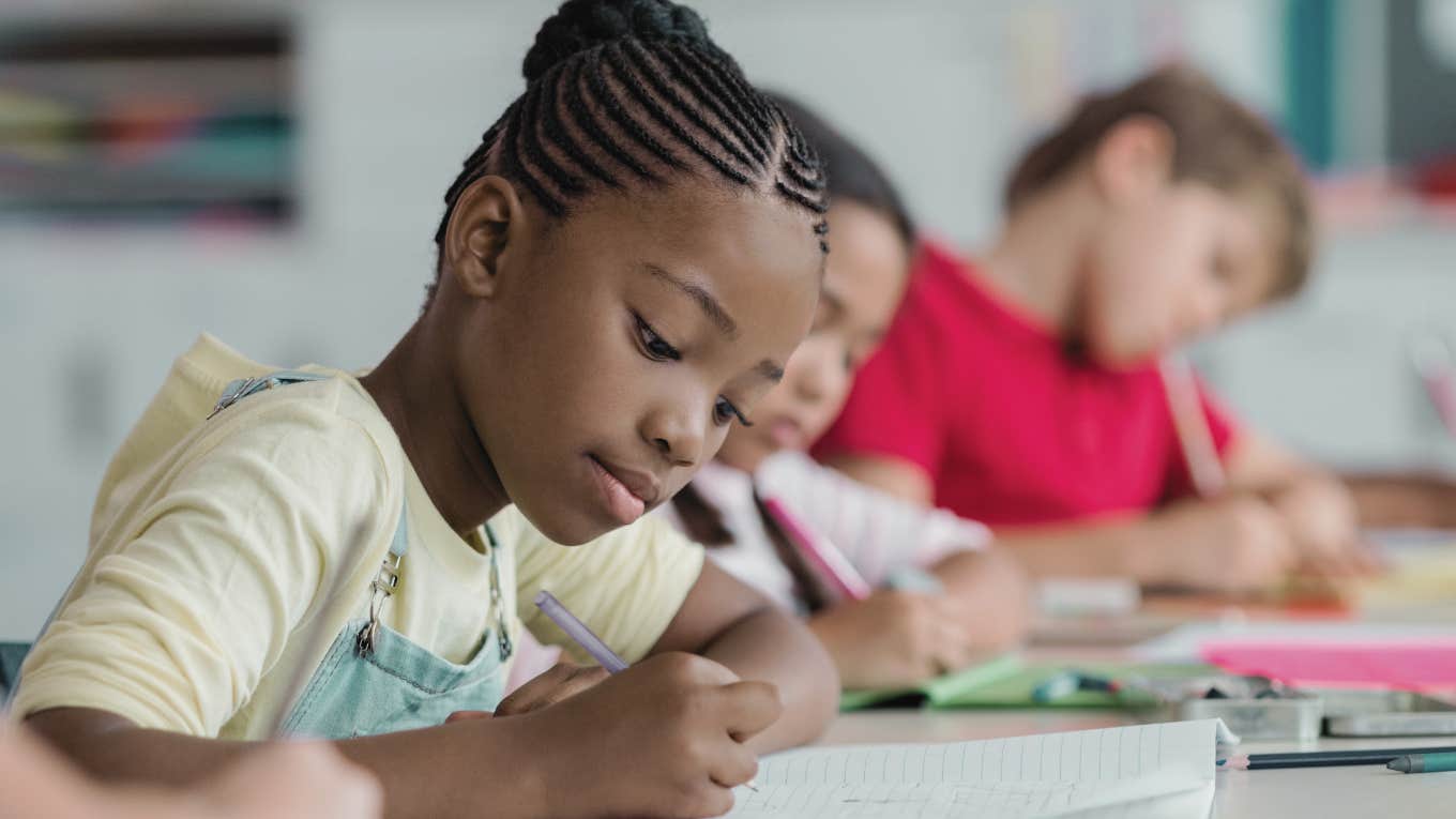 black student writing in notebook while sitting in class