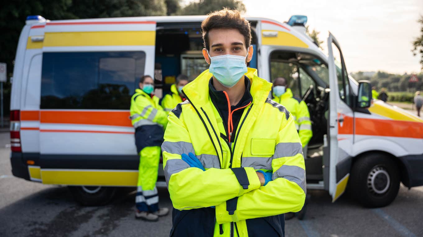 paramedic standing in front of truck with arms crossed and mask on