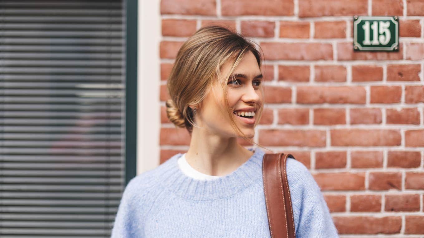 woman standing outside apartment building with hair in a bun