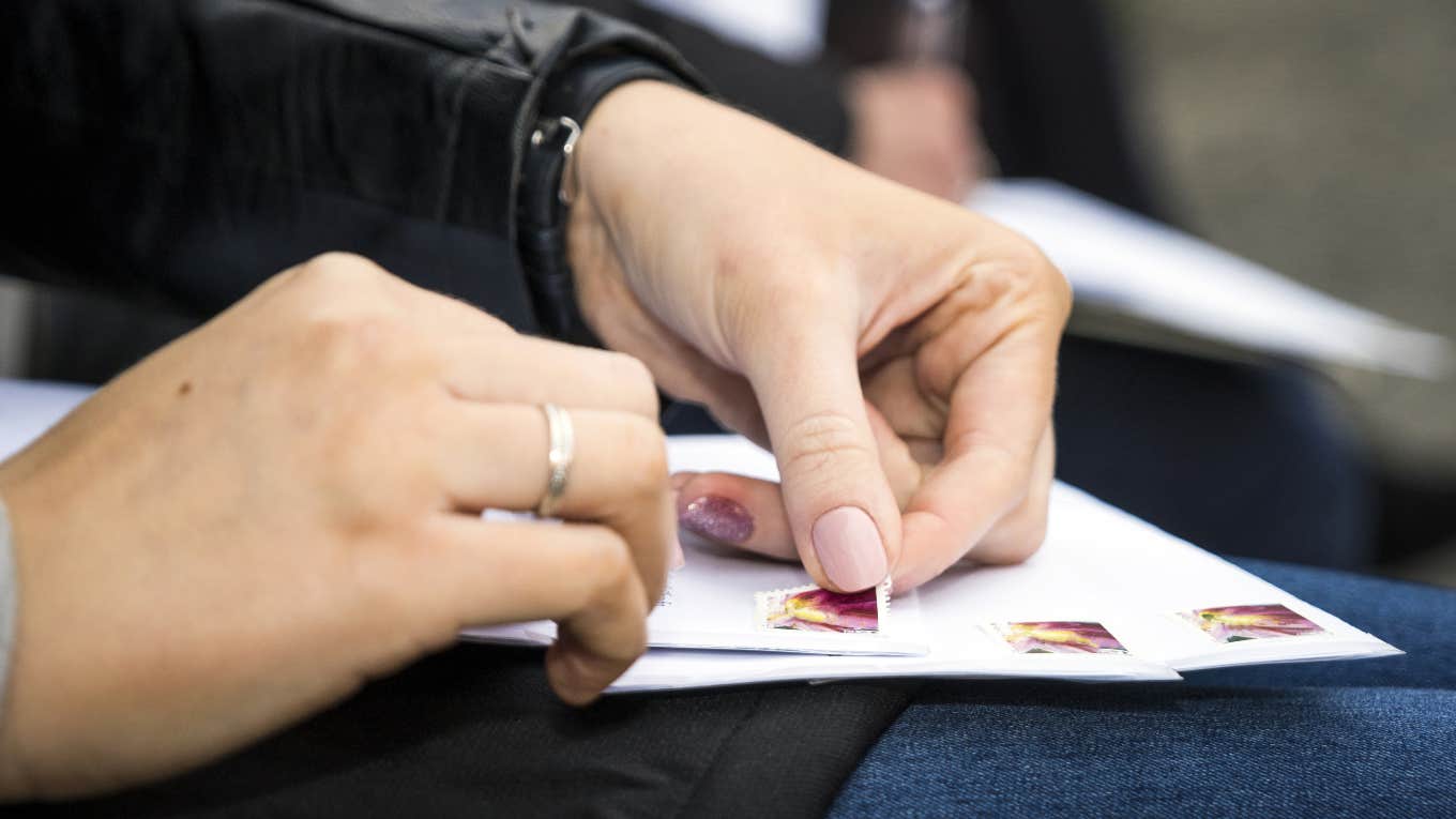 woman putting stamps on envelopes