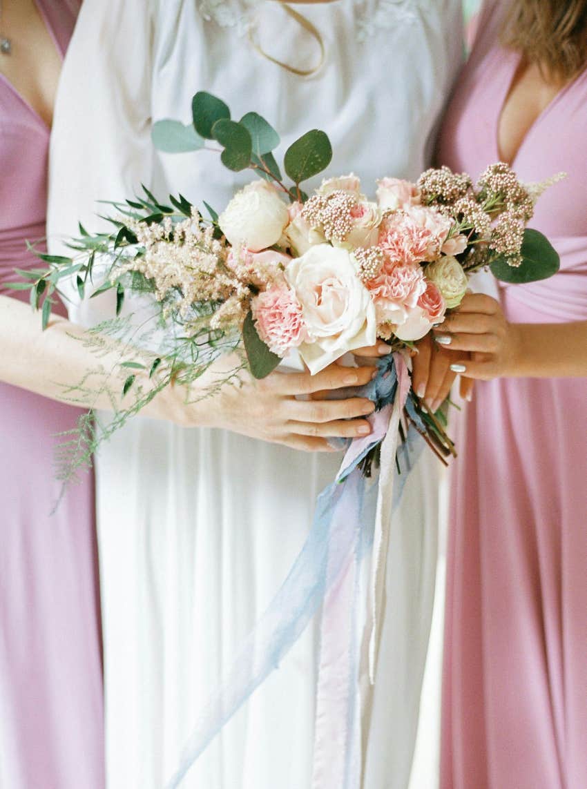 bride standing with bridesmaids holding bouquet of flowers