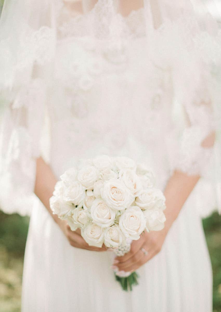 bride covered by veil holding flowers