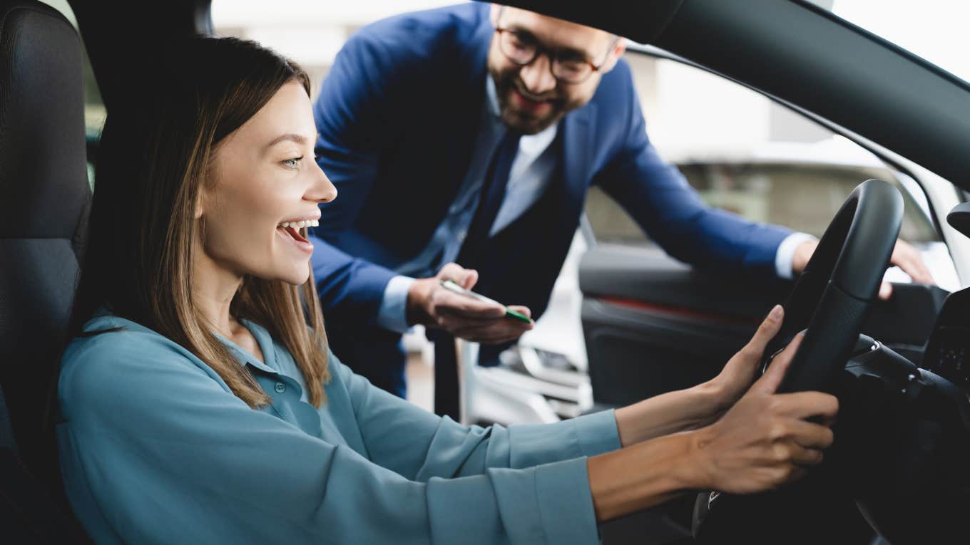 car salesman showing woman a car