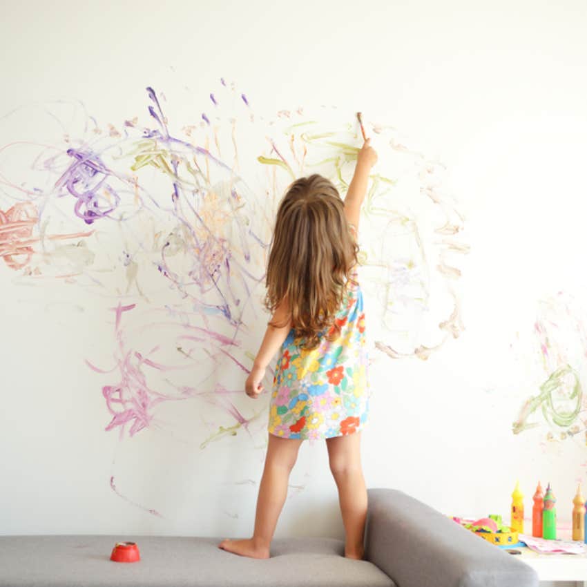 little girl drawing on wall