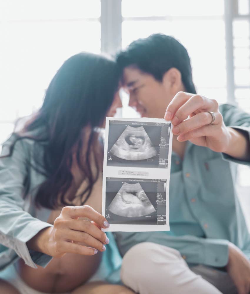 happy couple holding ultrasound photos
