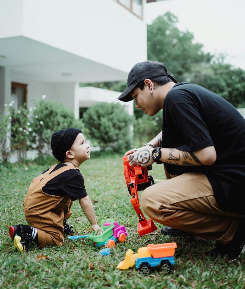 dad and toddler playing trucks in the yard 