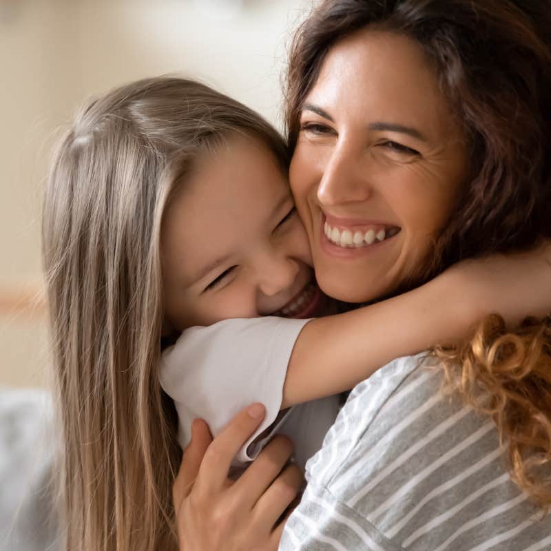 mother and daughter smiling while hugging