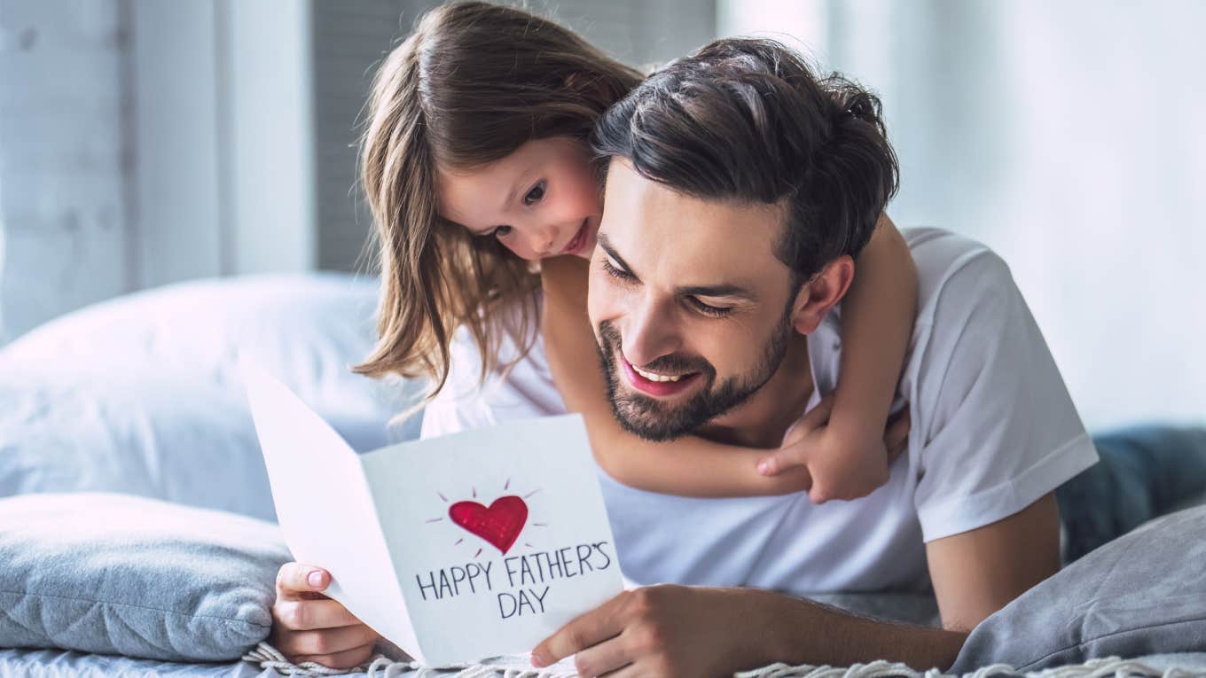 dad reading father's day card while daughter hangs on his back