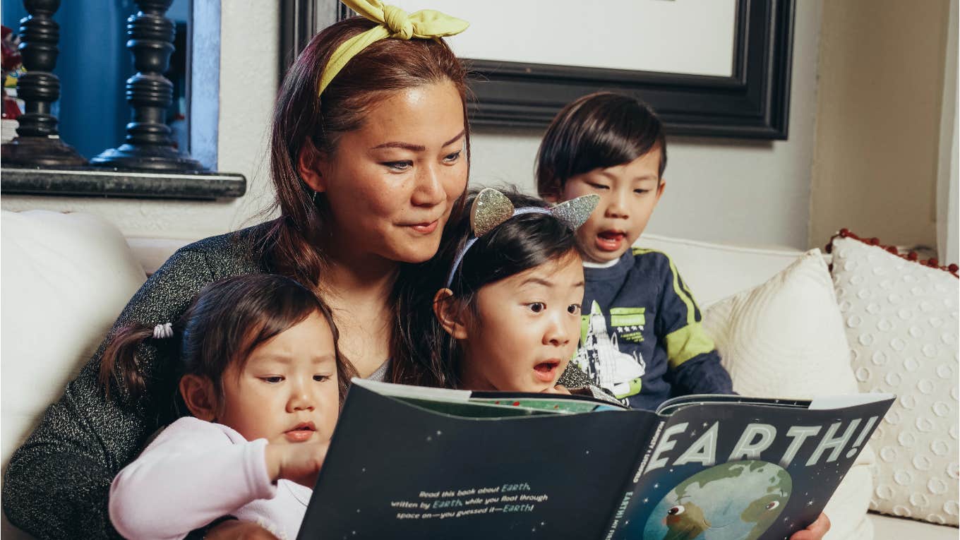 single mom reads a book to her three kids 