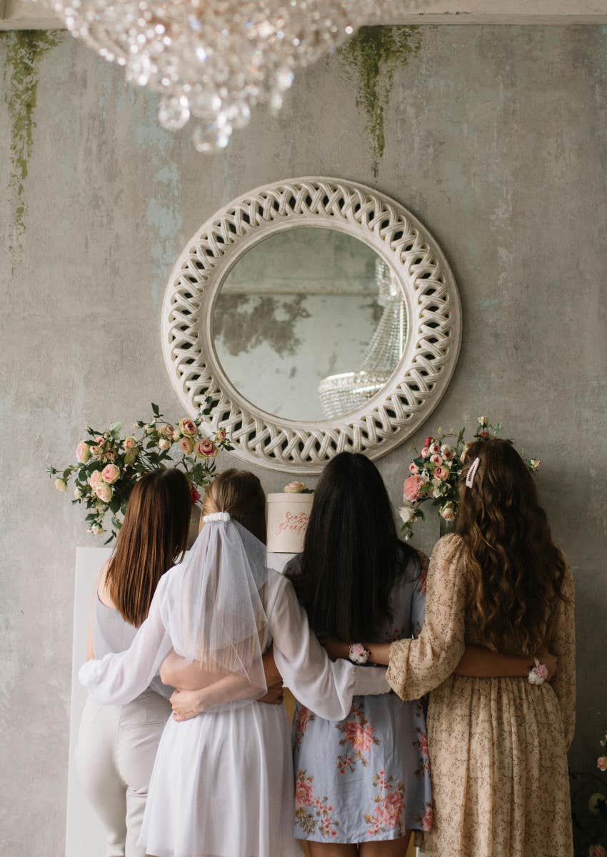 group of friends standing around a mirror at a bridal shower