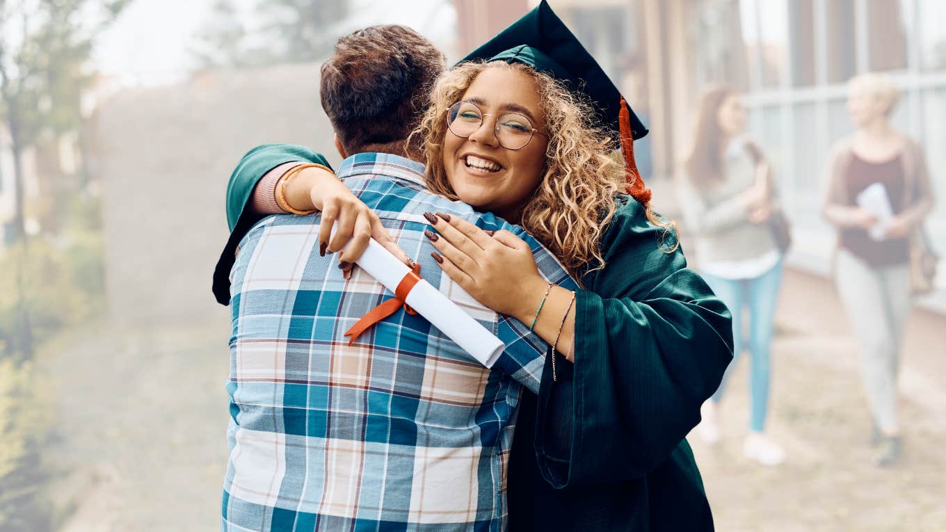 High school graduate hugging parent at graduation. 