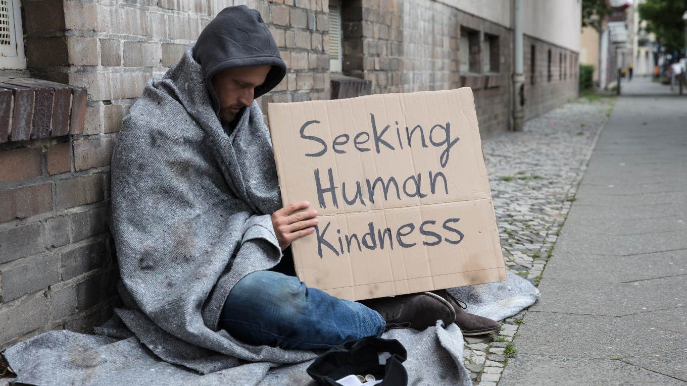 homeless man holding sign
