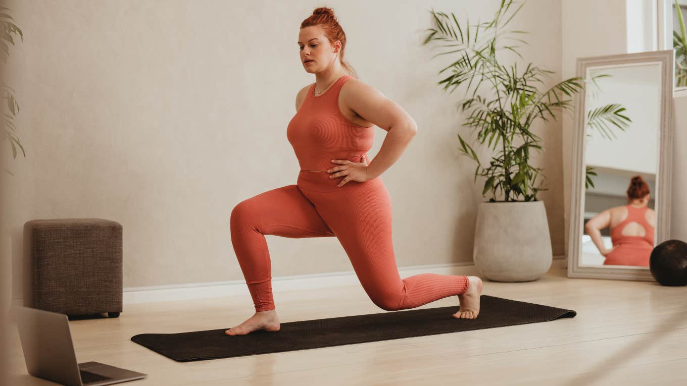 woman doing work out video on laptop in room with yoga mat