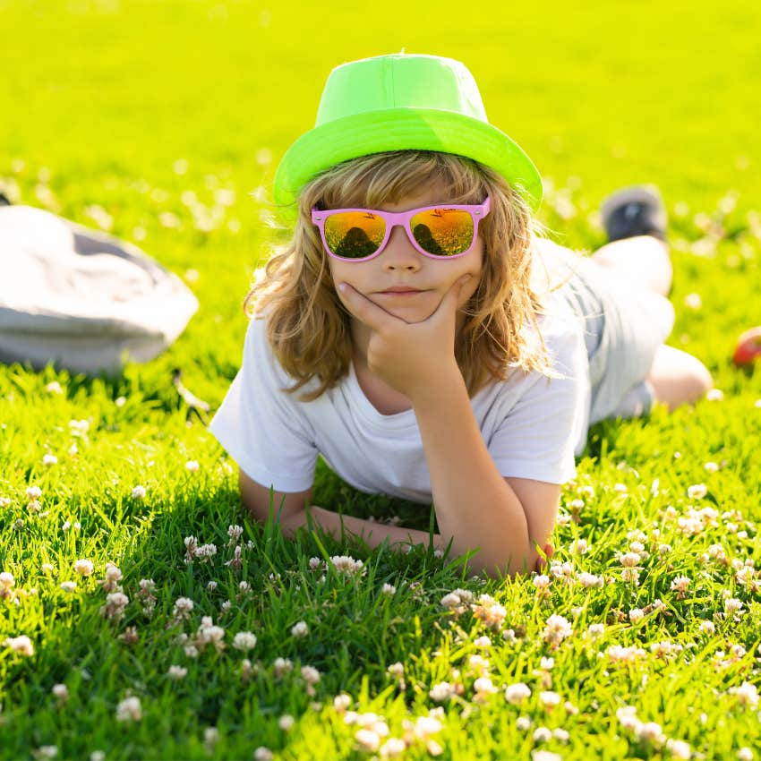 Little kid enjoying summer by laying in the grass outside. 