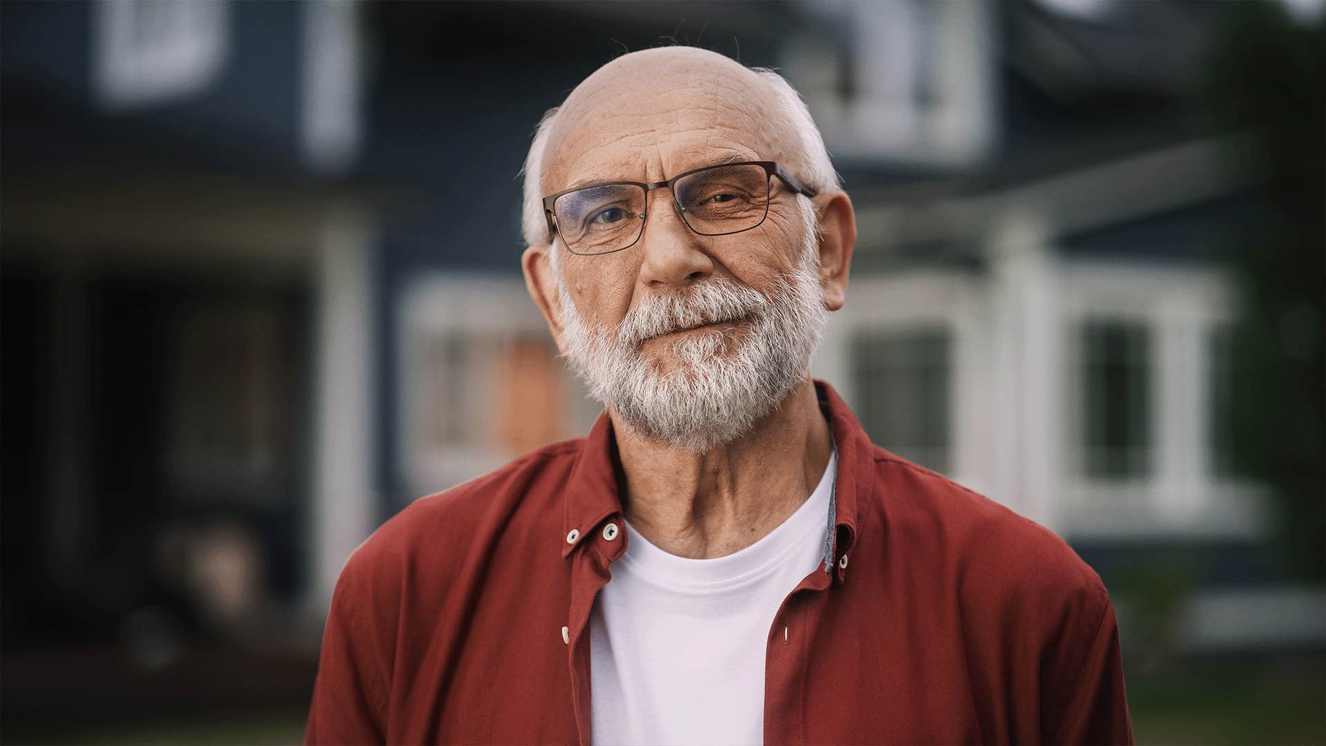 older man looking directly at the camera outside home