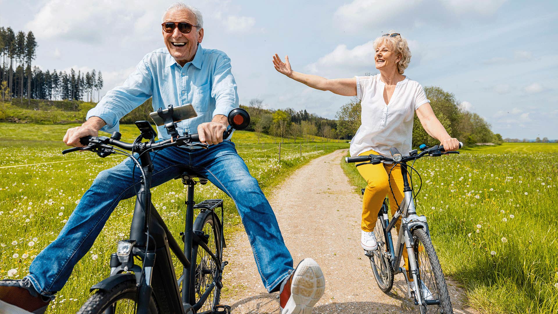 older couple having fun riding bicycles and laughing outside