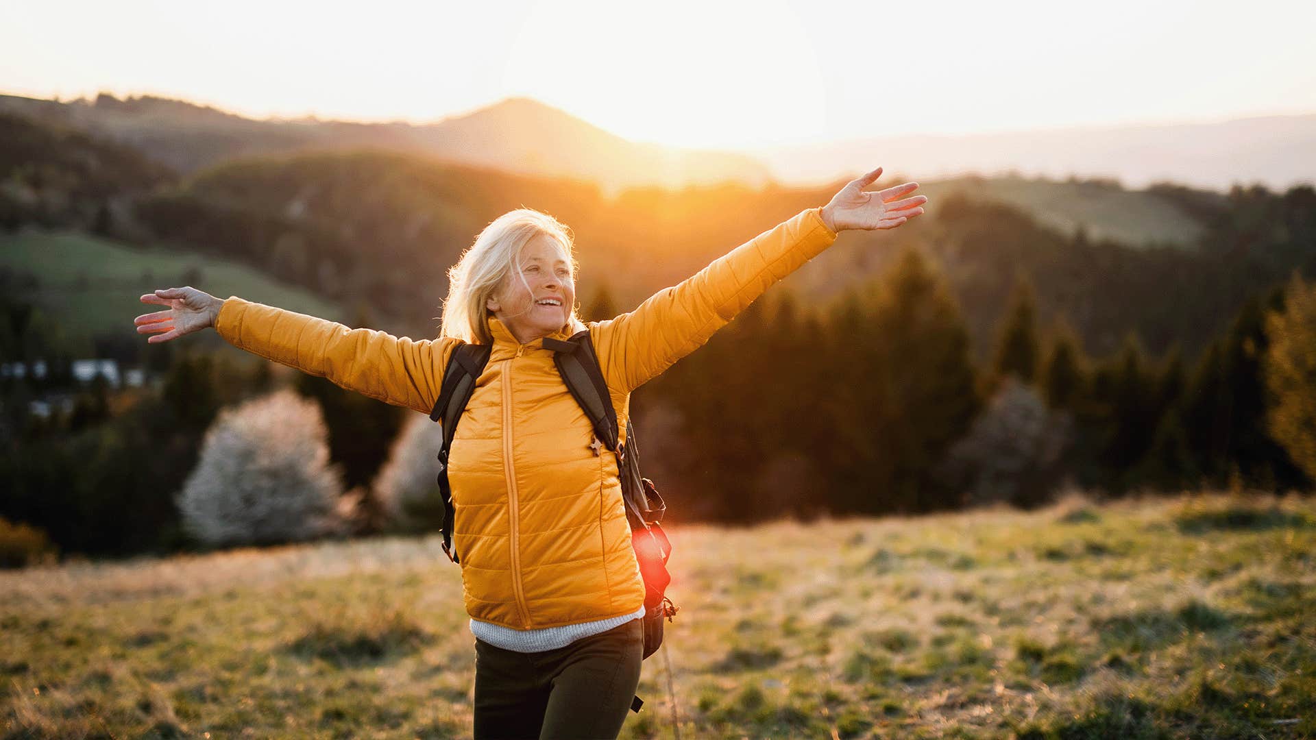 Older woman hiking a mountain in a yellow jacket