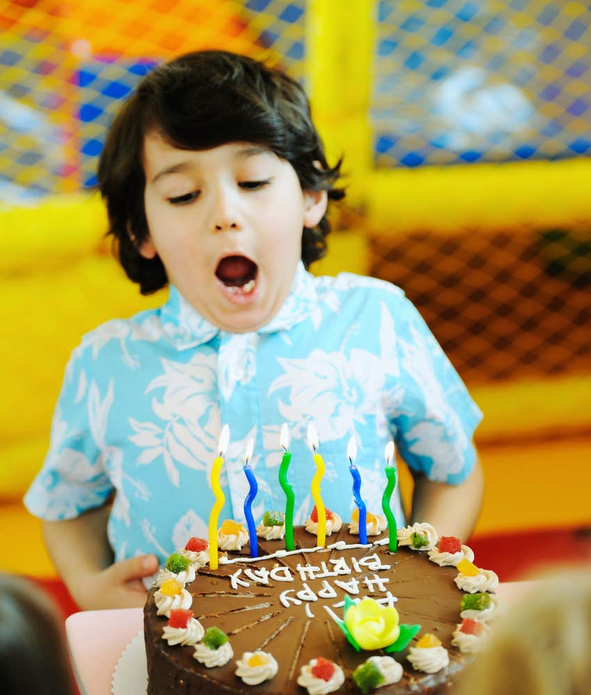 little boy blowing out candles on birthday cake