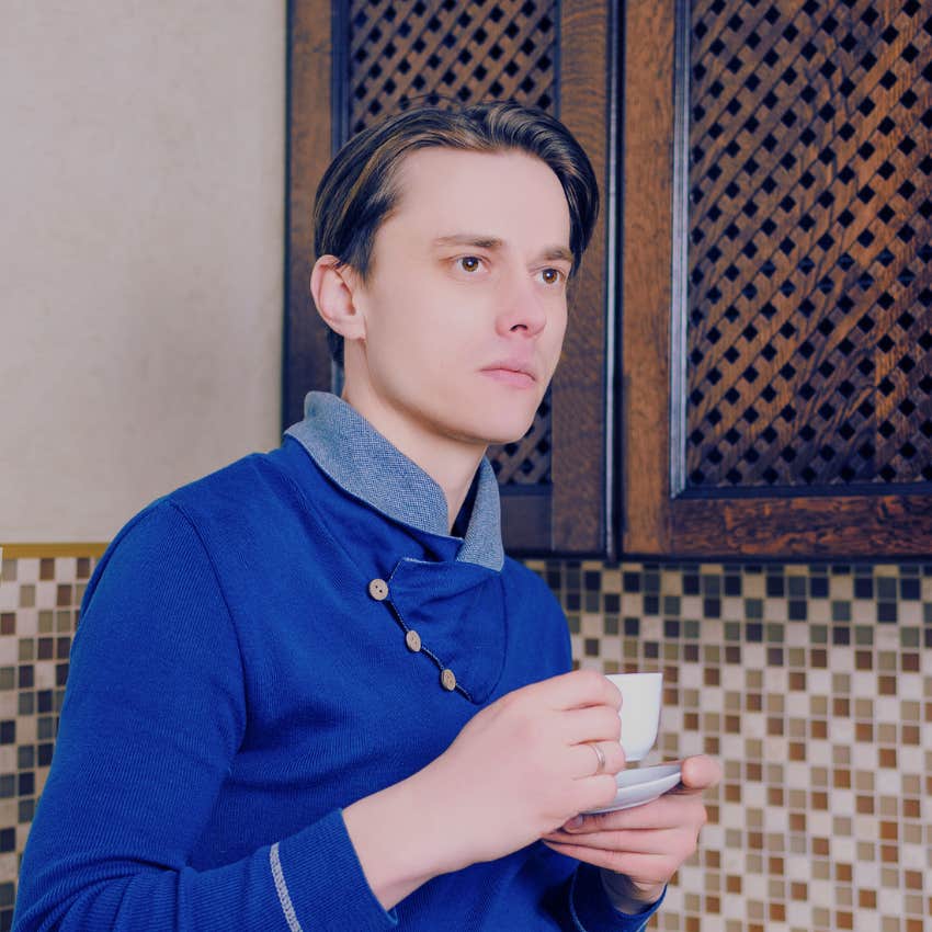 man drinking a cup of tea in a blue sweater