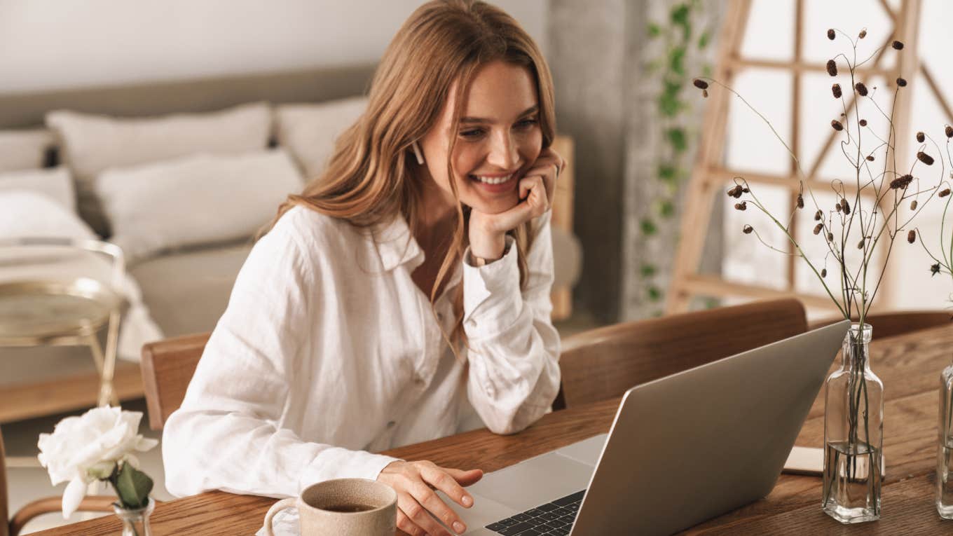 business woman sit indoors in office using laptop computer listening music with earphones.