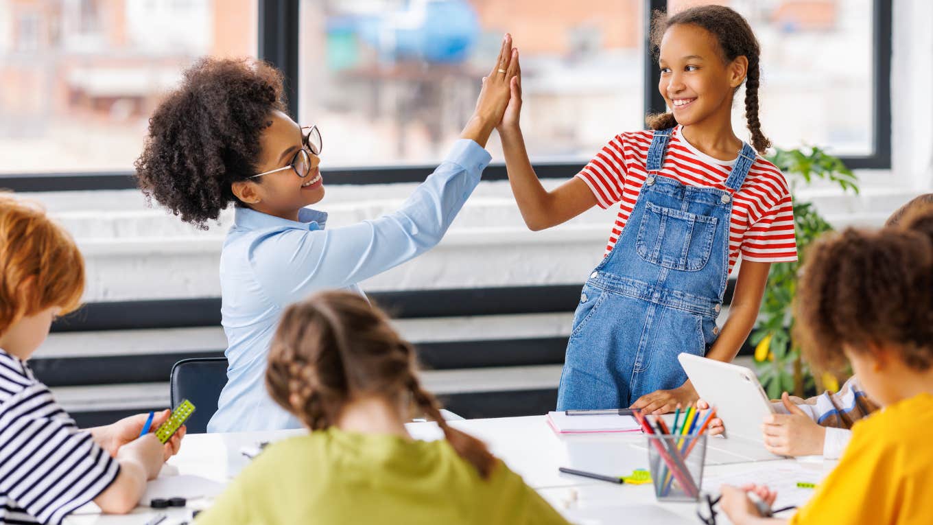 Students giving a high five to her teacher for winning a pool party.