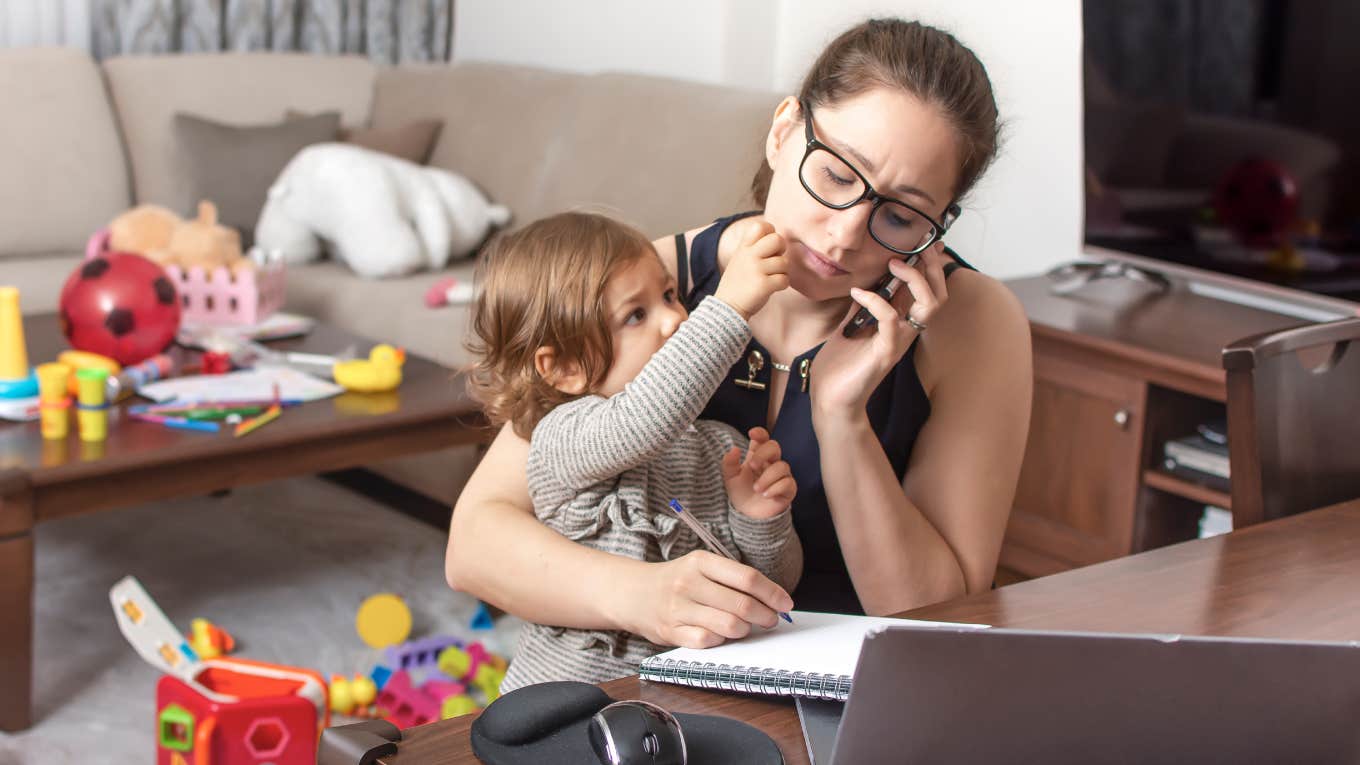 stressed mom working on laptop with toddler sitting on her lap