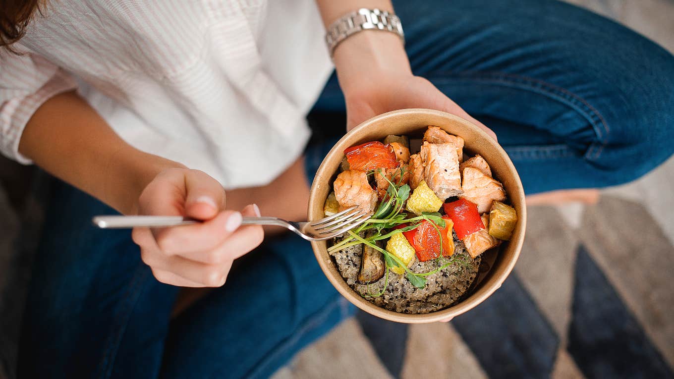 woman sitting cross legged holding a bowl of healthy food