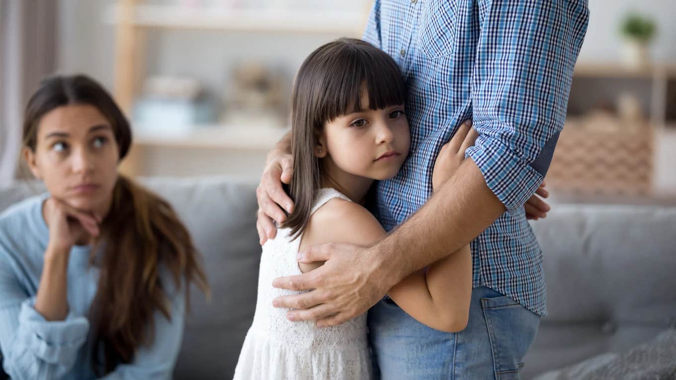 mom watching young girl hug her father