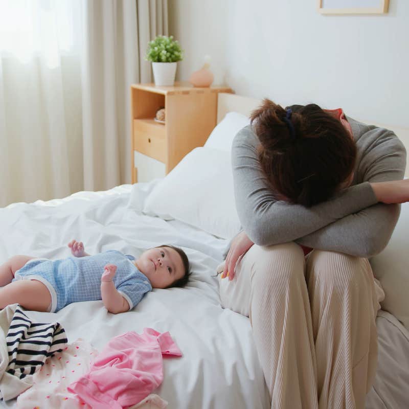 mother has postpartum depression with her baby who is lying on bed