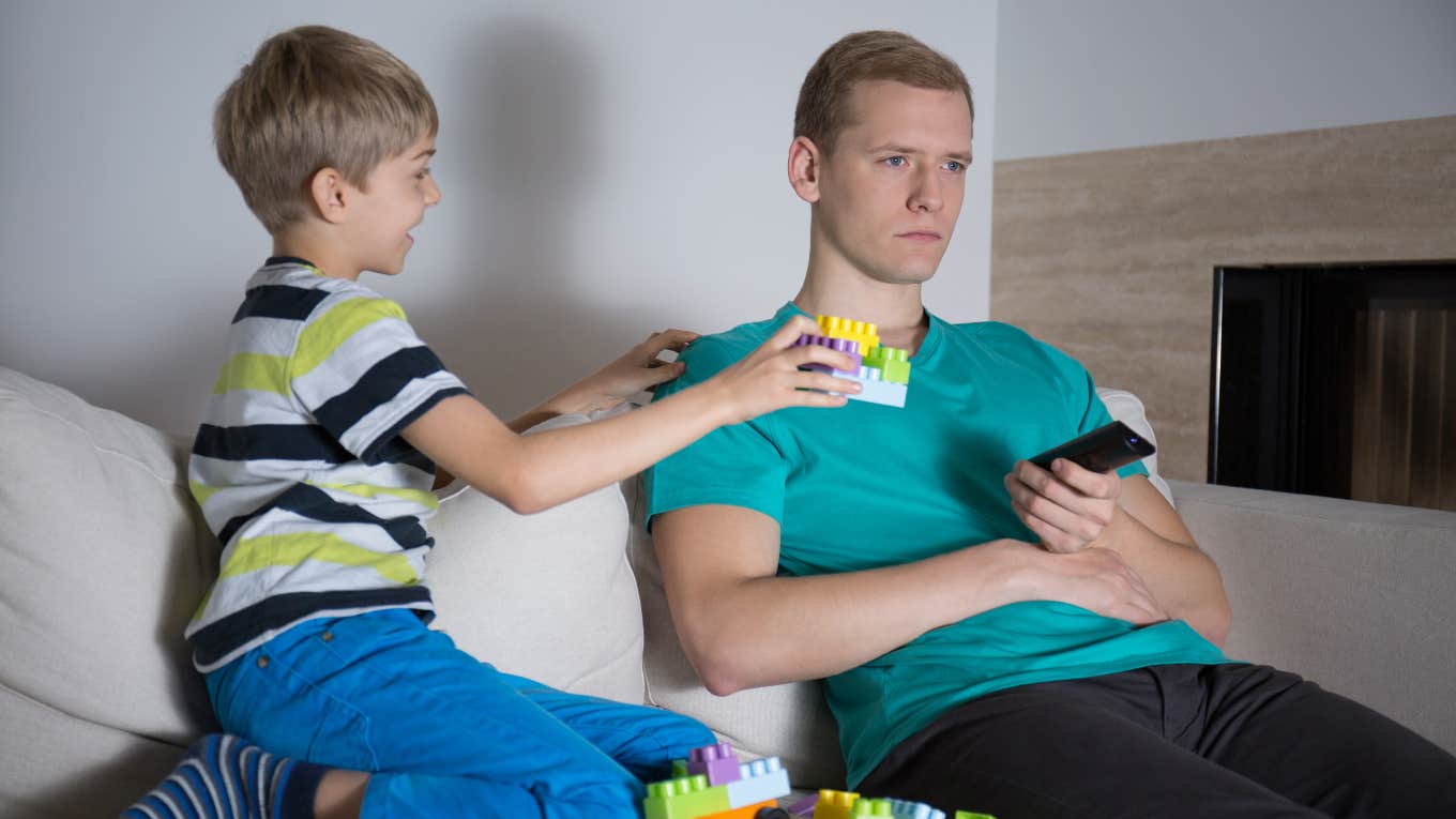 dad not paying attention to son trying to show him legos