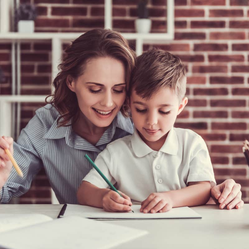 woman and her little son are drawing and smiling while sitting in office